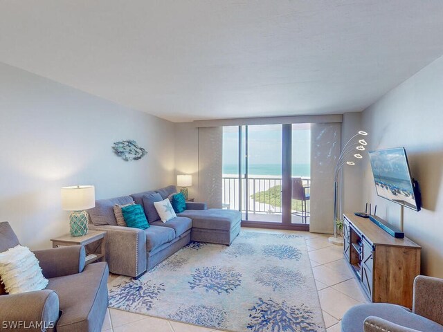 living room featuring a wall of windows, a water view, and light tile floors