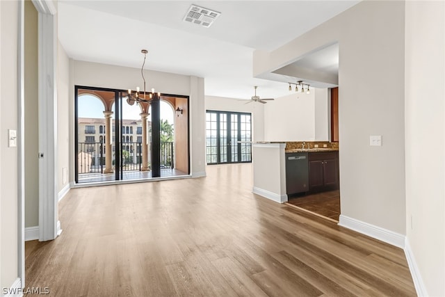 unfurnished living room with ceiling fan with notable chandelier, hardwood / wood-style floors, and rail lighting