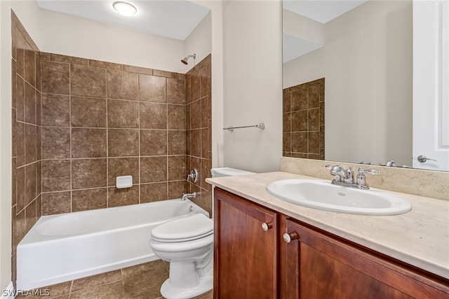 full bathroom featuring vanity with extensive cabinet space, tiled shower / bath, toilet, and tile floors