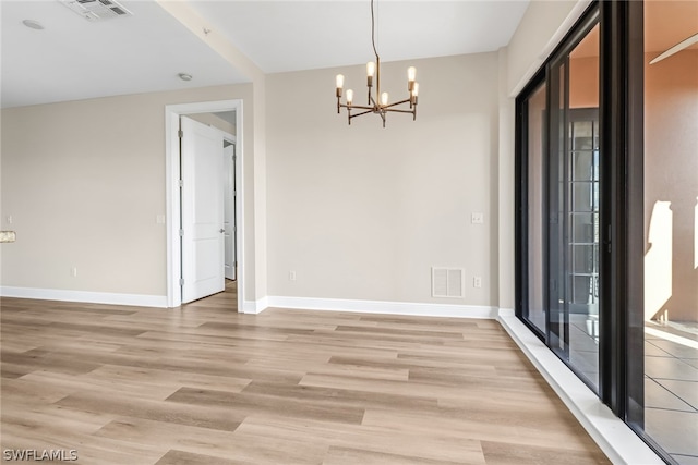 spare room with light hardwood / wood-style flooring and an inviting chandelier