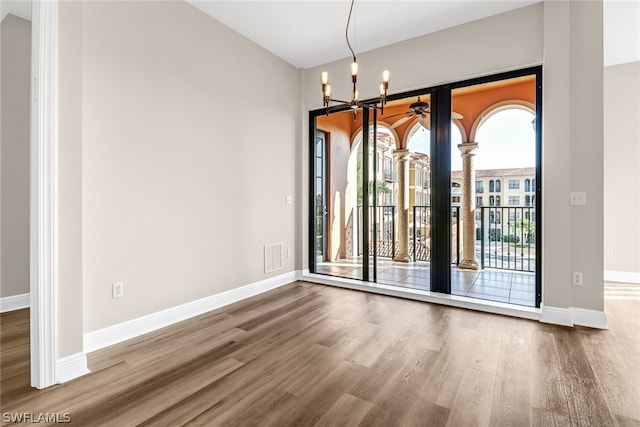 unfurnished room featuring a notable chandelier and hardwood / wood-style flooring