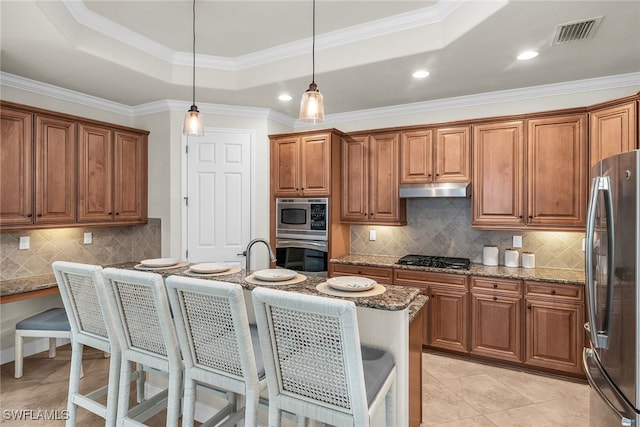 kitchen featuring light stone counters, a tray ceiling, ornamental molding, pendant lighting, and stainless steel appliances