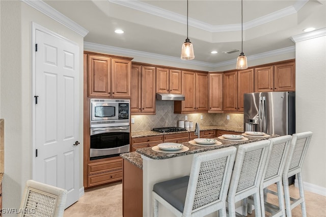 kitchen with a breakfast bar, a kitchen island with sink, dark stone counters, pendant lighting, and stainless steel appliances