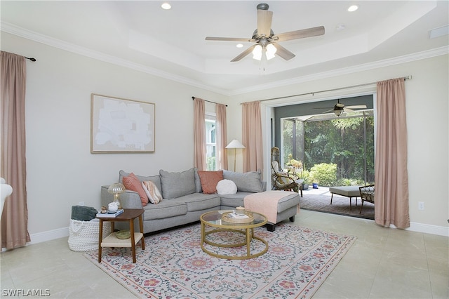 living room featuring ceiling fan, a tray ceiling, and ornamental molding