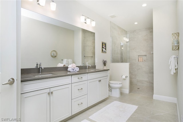 bathroom featuring tile patterned floors, tiled shower, vanity, and toilet