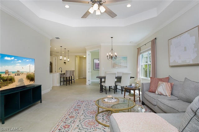 tiled living room featuring sink, ornamental molding, ceiling fan with notable chandelier, and a raised ceiling