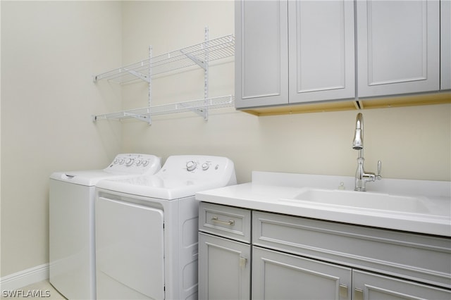 laundry room with sink, washing machine and dryer, and cabinets