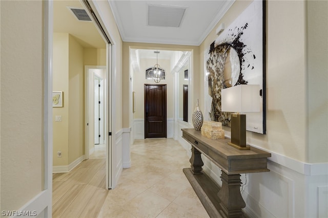 hall with crown molding and an inviting chandelier