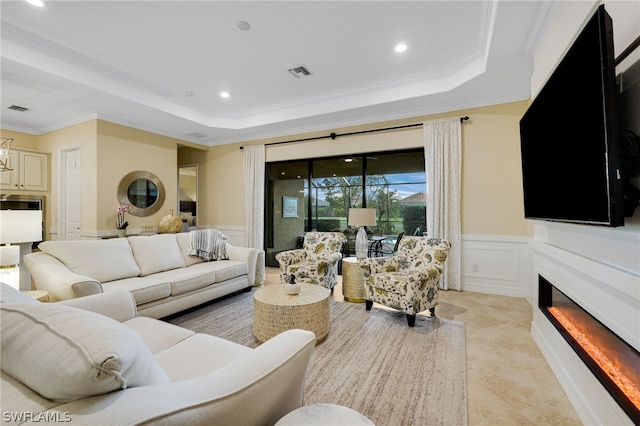 living room featuring a raised ceiling and ornamental molding