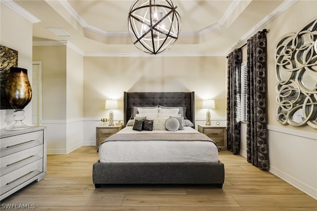 bedroom featuring a raised ceiling, a notable chandelier, light wood-type flooring, and ornamental molding