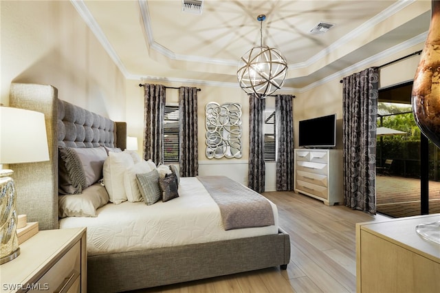 bedroom with a tray ceiling, light hardwood / wood-style flooring, a notable chandelier, and crown molding