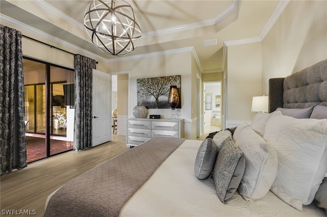 bedroom featuring hardwood / wood-style floors, access to exterior, ornamental molding, a tray ceiling, and a notable chandelier