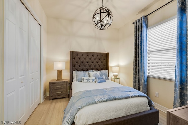 bedroom featuring a closet, a notable chandelier, and light wood-type flooring