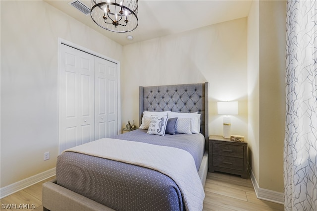 bedroom with a closet, a notable chandelier, and light wood-type flooring