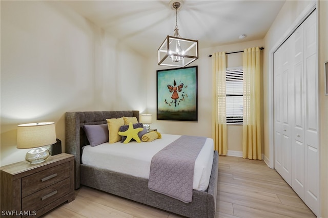 bedroom with a notable chandelier, light wood-type flooring, and a closet