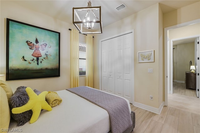 bedroom featuring an inviting chandelier, light hardwood / wood-style flooring, and a closet