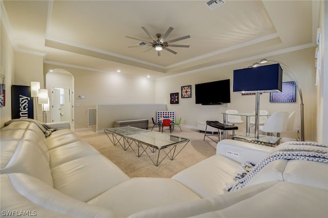 carpeted living room with ceiling fan, a raised ceiling, and crown molding