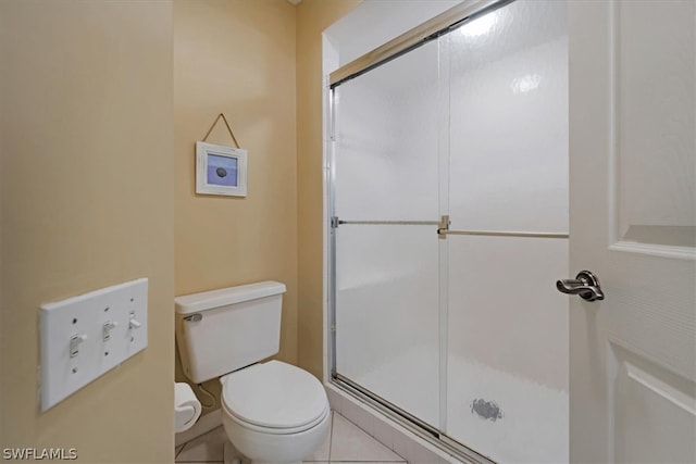 bathroom featuring an enclosed shower, toilet, and tile flooring