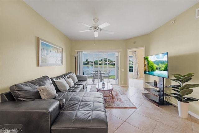 tiled living room featuring ceiling fan and a water view