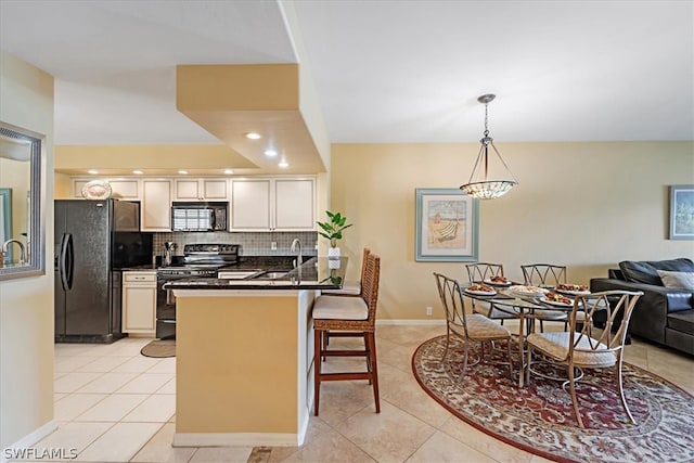 kitchen featuring light tile flooring, backsplash, white cabinetry, a breakfast bar area, and black appliances