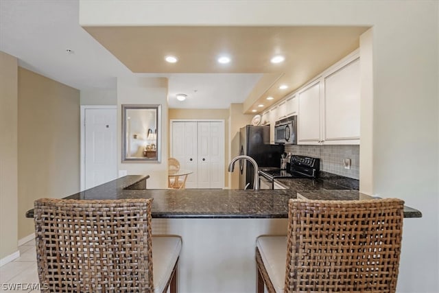 kitchen featuring a kitchen breakfast bar, white cabinets, kitchen peninsula, stainless steel appliances, and light tile floors