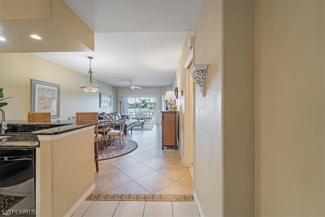 kitchen with pendant lighting, dark stone countertops, ceiling fan, and light tile floors