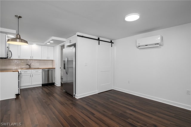 kitchen featuring a wall unit AC, dark hardwood / wood-style flooring, hanging light fixtures, and appliances with stainless steel finishes