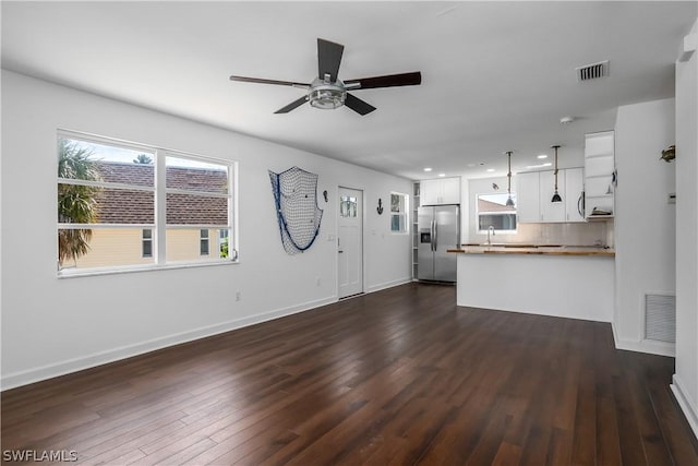 unfurnished living room featuring dark hardwood / wood-style flooring, ceiling fan, and sink