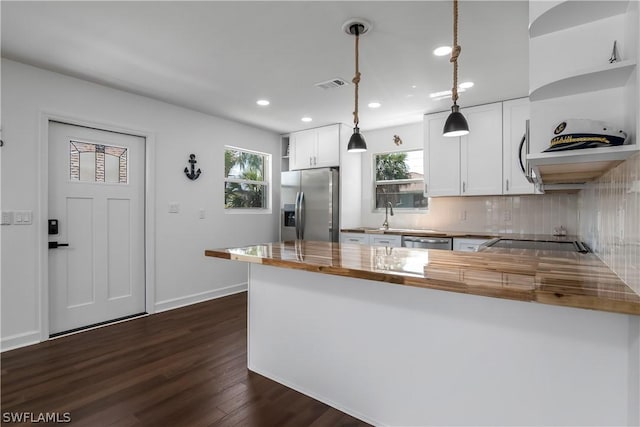 kitchen with white cabinetry, stainless steel appliances, decorative light fixtures, and wood counters