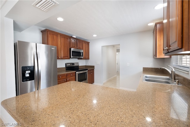 kitchen featuring light stone counters, appliances with stainless steel finishes, sink, and light tile flooring