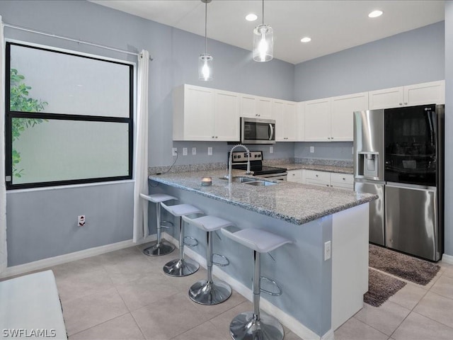 kitchen featuring appliances with stainless steel finishes, white cabinets, kitchen peninsula, and decorative light fixtures