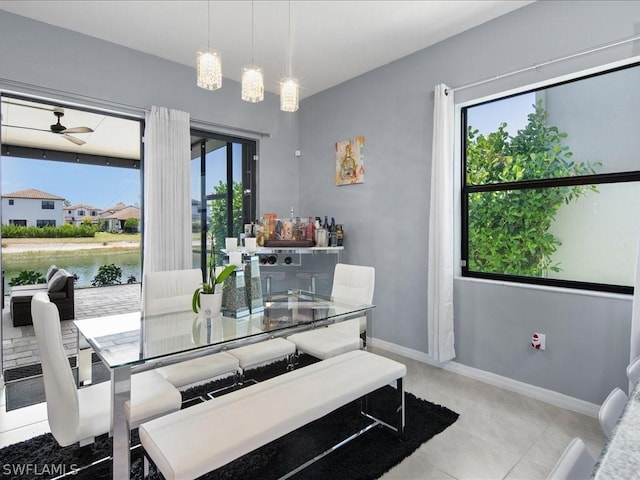 dining area with ceiling fan, light tile patterned flooring, and a water view