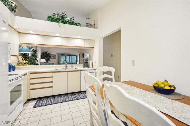 kitchen with dishwasher, stove, sink, light tile patterned floors, and kitchen peninsula