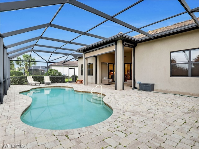 view of pool with glass enclosure and a patio