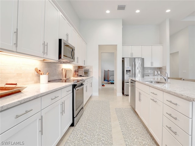 kitchen featuring white cabinetry, stainless steel appliances, tasteful backsplash, and sink