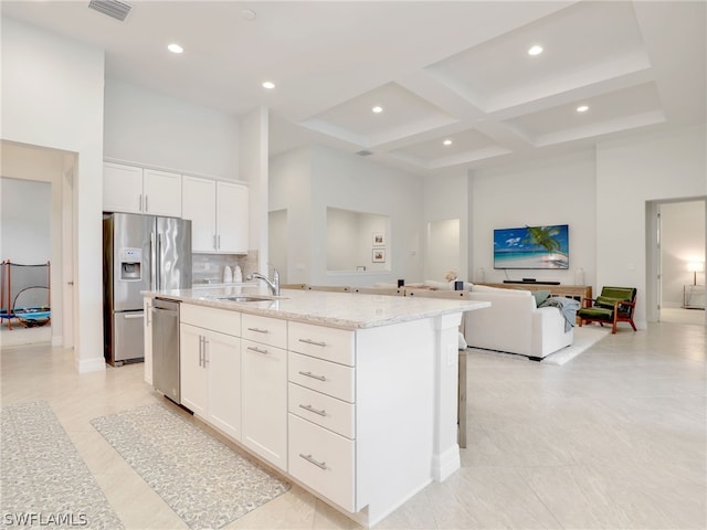 kitchen featuring white cabinets, coffered ceiling, stainless steel appliances, an island with sink, and sink