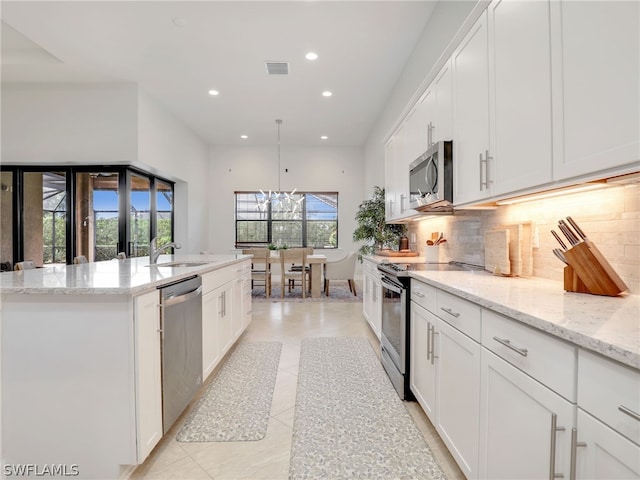 kitchen featuring stainless steel appliances, decorative light fixtures, light tile flooring, a kitchen island with sink, and white cabinetry