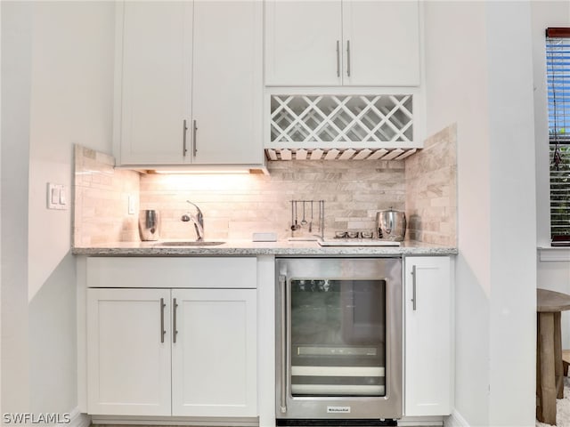 bar featuring wine cooler, sink, tasteful backsplash, and white cabinetry