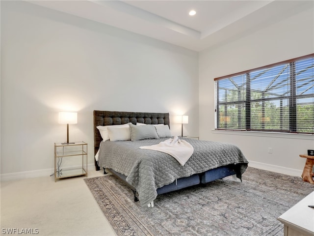 carpeted bedroom featuring a tray ceiling and multiple windows