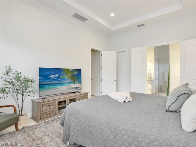 bedroom featuring a raised ceiling and ensuite bath