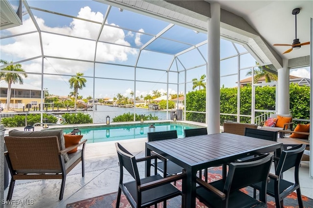 view of patio / terrace with a water view, a lanai, a ceiling fan, and an outdoor pool