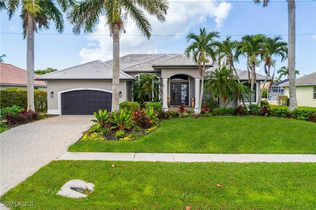 view of front facade with an attached garage, decorative driveway, french doors, a front yard, and stucco siding