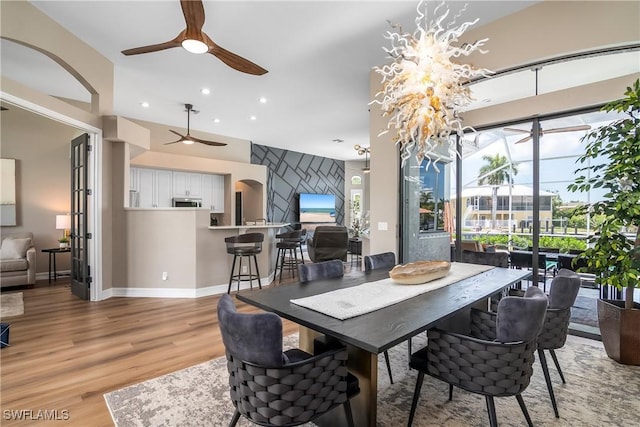 dining room with baseboards, ceiling fan with notable chandelier, recessed lighting, and light wood-style floors