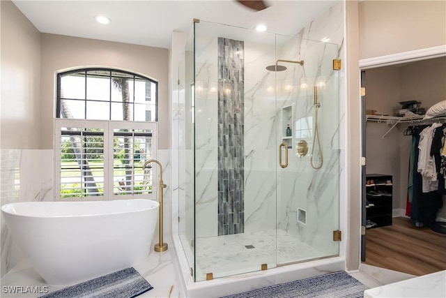 bathroom featuring a marble finish shower, marble finish floor, a spacious closet, a freestanding bath, and recessed lighting