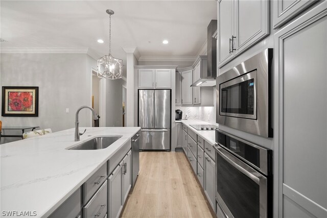 kitchen with hanging light fixtures, backsplash, stainless steel appliances, sink, and light wood-type flooring