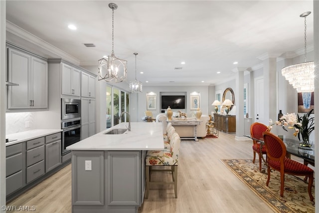 kitchen featuring decorative light fixtures, light hardwood / wood-style flooring, gray cabinetry, and stainless steel appliances