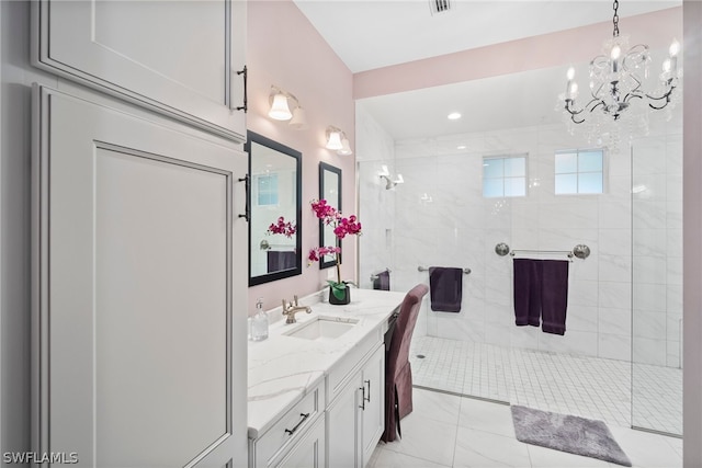 bathroom with tile flooring, tiled shower, vanity with extensive cabinet space, and an inviting chandelier