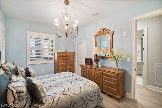 bedroom featuring light hardwood / wood-style flooring, an inviting chandelier, and connected bathroom