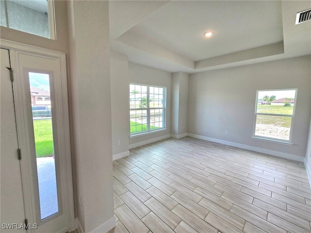 entryway with light hardwood / wood-style flooring and a tray ceiling