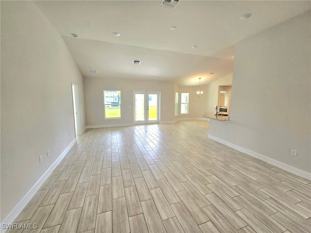 unfurnished living room with vaulted ceiling, light hardwood / wood-style flooring, and a chandelier